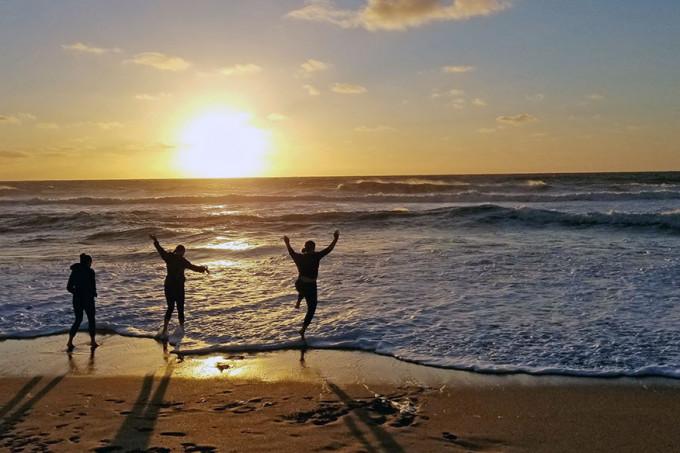 Three Susquehanna students in Argentina on a beach during sunrise.